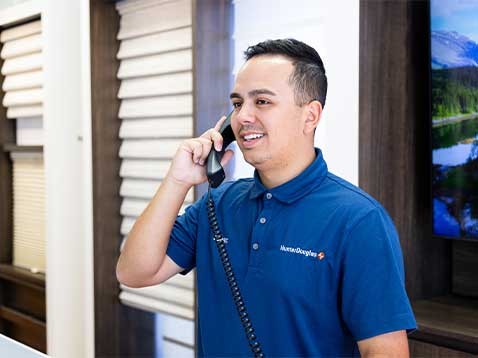 A man wearing a Hunter Douglas polo speaking on a telephone